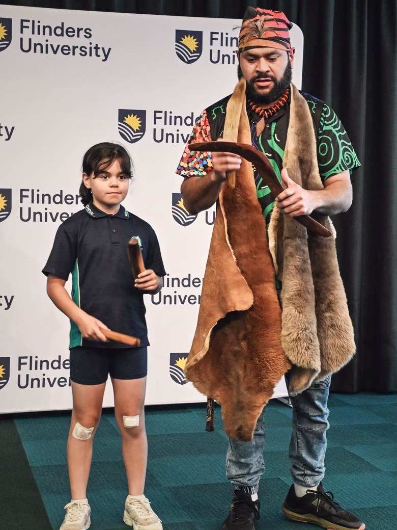 Petiola Wilson showing a boomerang to a young student at a university event