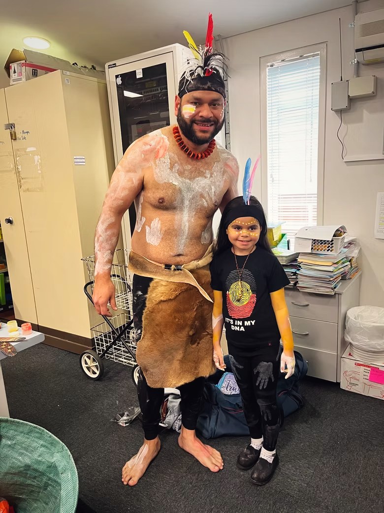 Petiola Wilson painted up for ceremony standing with a young family member